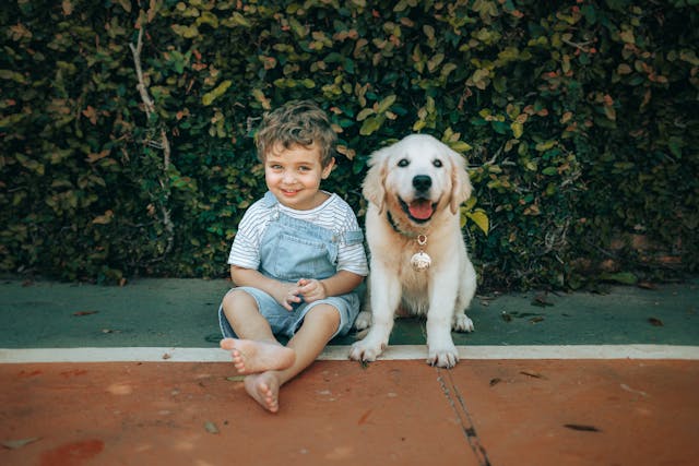 A little boy and a puppy on the sidewalk.